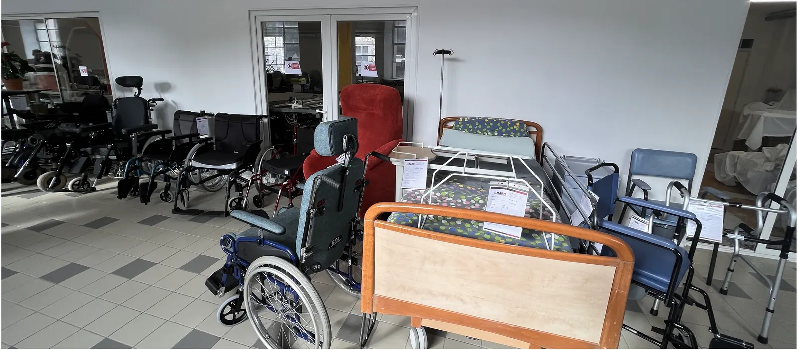 Fauteuils roulants, fauteuil releveur et lit médicalisé reconditionnés, alignés dans un espace d’exposition
